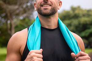 Smiling athletic man resting after fitness workout in green park