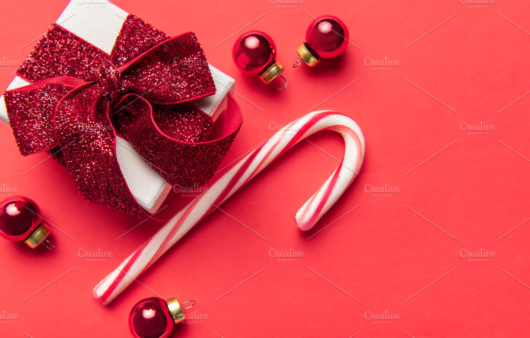 Christmas gift box, candy cane, and ornaments on red background, a Holiday Photo by Olena Rudo