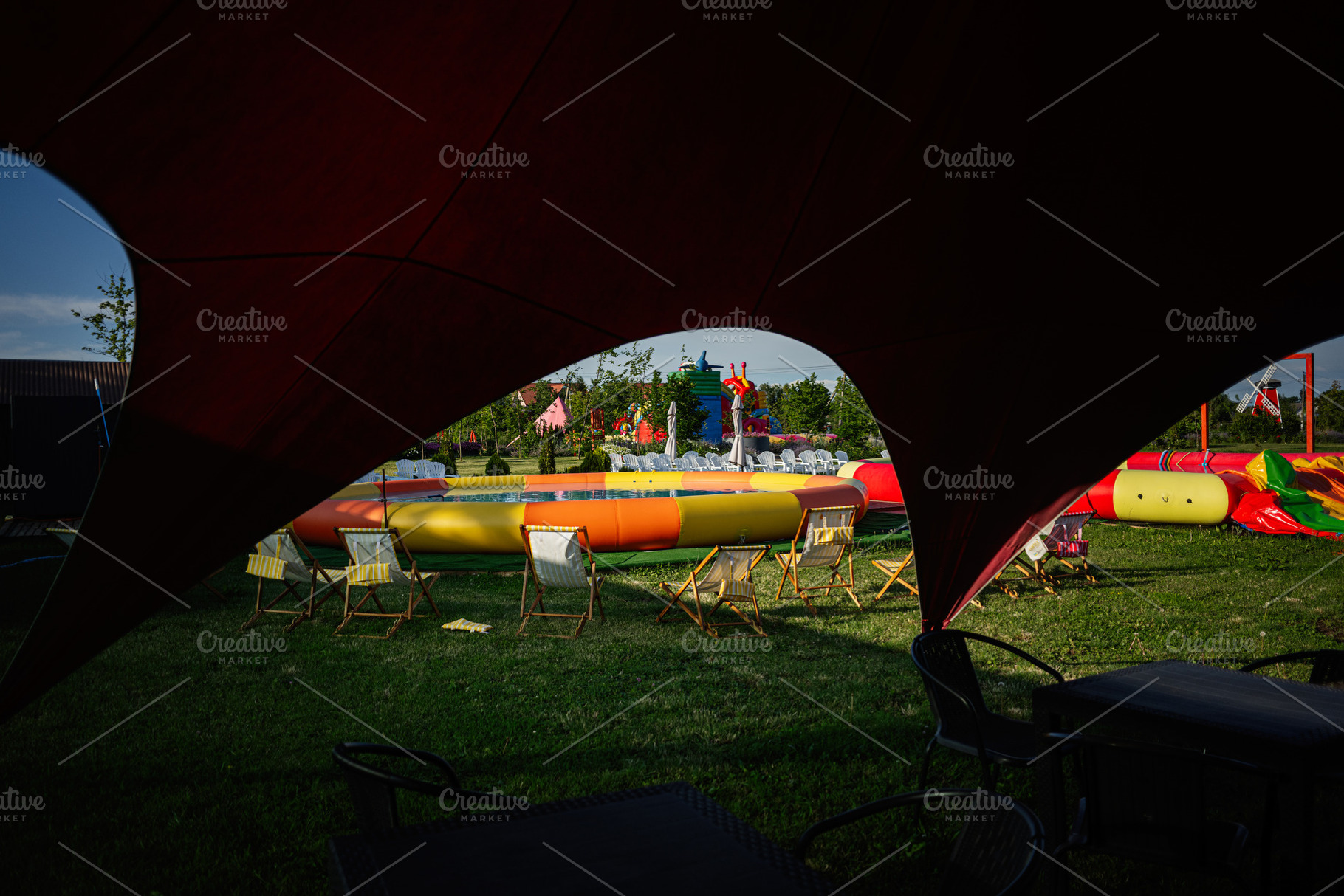 Outdoor seating around inflatable play area during vibrant summer day festival, a Photo by AS photostudio