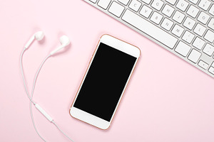 Smartphone, headphones and computer keyboard on pink and blue background. Technology