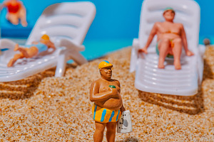 miniature man wearing striped shorts on the sand, a Photo by Nito