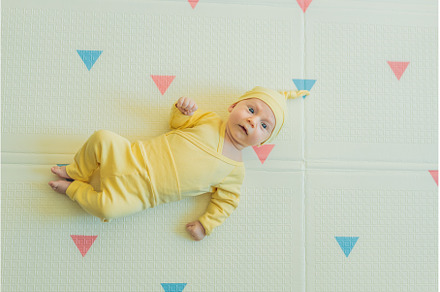 Adorable baby in a yellow hat lying