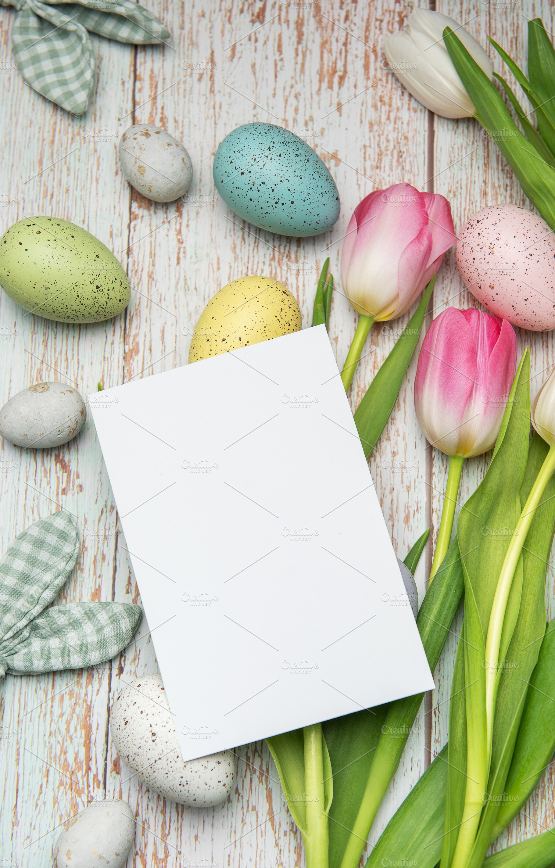 Easter eggs and tulips framing a blank card on rustic wooden bac, a Holiday Photo by Olena Rudo