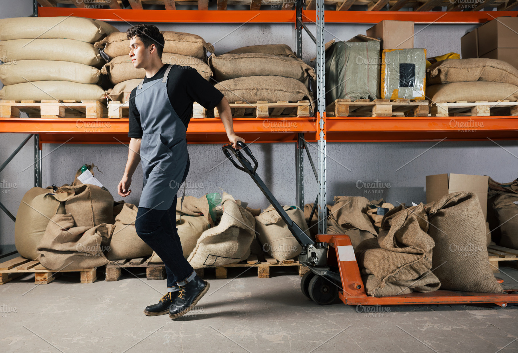 Male in apron pulling truck, an Industrial Photo by Artem Varnitsin