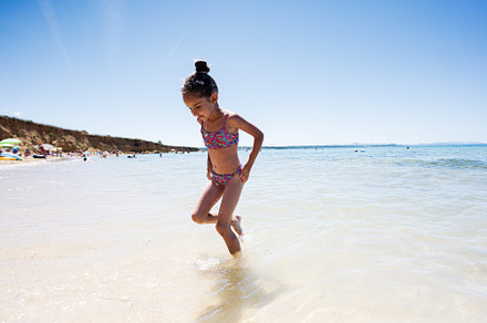 Young girl playing on the beach in colorful swimsuit on sunny day in Croatia., a Person Photo by AS photostudio
