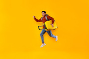 Emotional Male Tourist Jumping Carrying Suitcase Over Yellow Studio Background, a Photo by Prostock-Studio (Thumbnail 1 of 2)