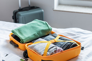 Open suitcase filled with clothes packing for travel, a Holiday Photo by Olena Rudo