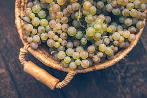 Basket with grapes on vintage rustic wooden barrel, table, a Food & Drink Photo by Mark Borbely
