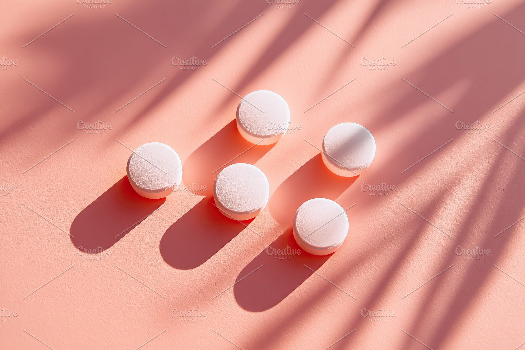 Close-up view of white round tablets casting shadows on soft pink surface, a Health & Medical Photo by AlyaAnd