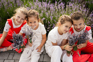 Group of happy children holding lavender bouquets outdoors in a sunny garden, a Photo by AS photostudio