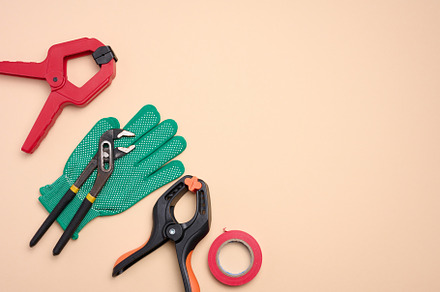 Green glove and metal universal adjustable wrench on a beige bac, an Abstract Photo by ndanko