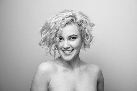 Headshot of gorgeous attractive young lady with curly hair smiling. Black and w