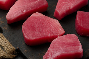 Raw tuna pieces on a wooden board, top view, a Food & Drink Photo by ndanko