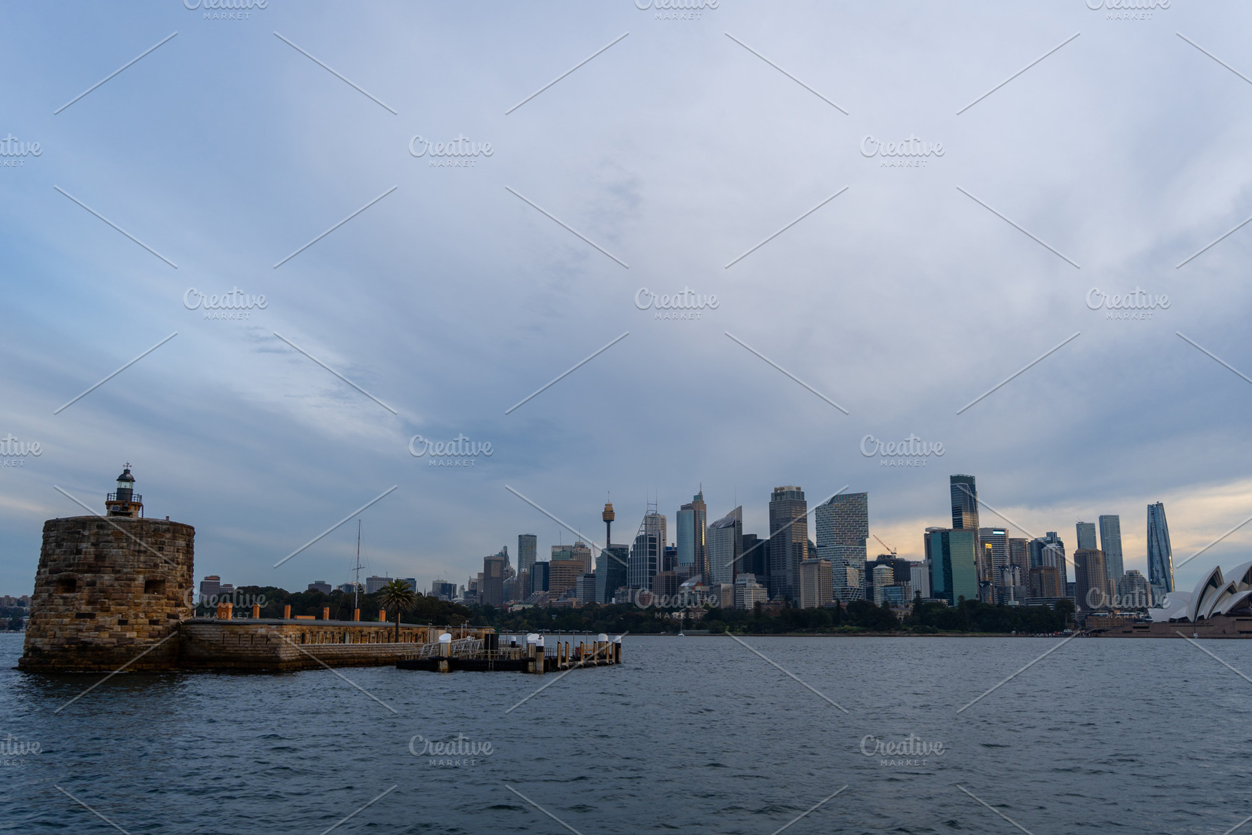Sydney skyline at sunset with golden reflections on the water, an Architecture Photo by GoodGoods