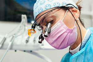 Dentist wearing magnifying glasses and mask performing dental checkup, a Photo by Antonio Gravante Market