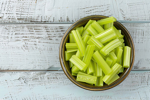Green fresh celery pieces in bowl on wooden table, a Food & Drink Photo by AlyaAnd