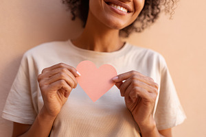 Woman holding a paper heart on pastel background, a Person Photo by AlyaAnd