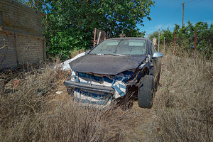 Abandoned crashed car on dry grass, a Transportation Photo by DanFLCreativo