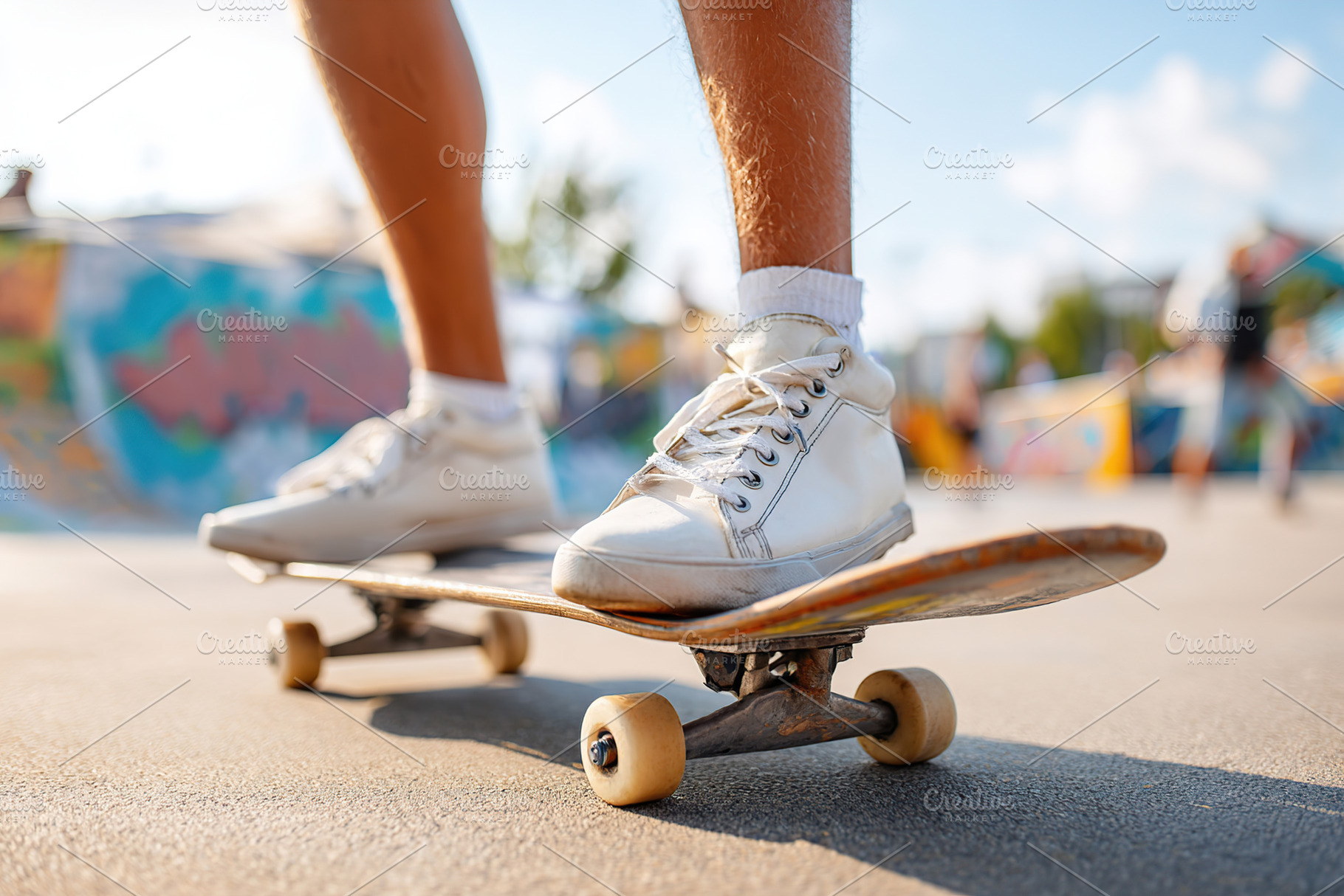 Practicing tricks on a skateboard at a sunny skatepark with colorful murals in, a Photo by AlyaAnd