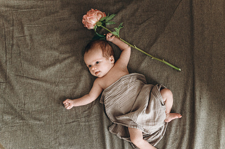 Happy Mothers day! Cute little baby with flower lying on brown b