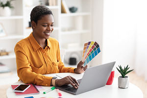 Joyful black lady working as web designer, office interior, a Photo by Prostock-Studio