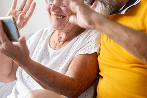 Senior couple waving during video call, a Person Photo by etorres69