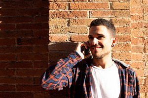 Young caucasian man smiling while talking on smartphone outdoors, a Person Photo by RF Images