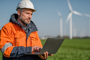 Engineer using laptop near wind turb, a Photo by Pixeness Studio