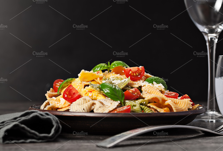 Multicolored Pasta On Dark Background Containing Background Basil And Cheese