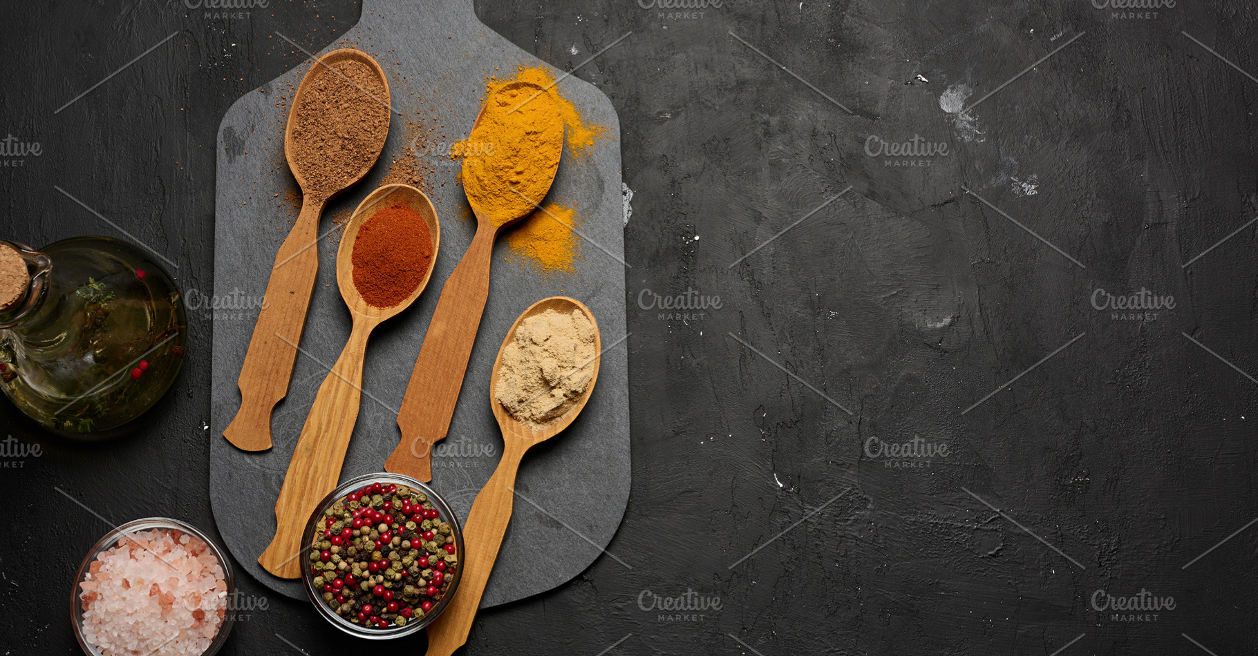 Multicolored ground spices in wooden spoons on a black board, sa, a Food & Drink Photo by ndanko