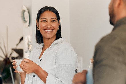 Woman drinking coffee, having conversation and bonding with her husband at home. Smiling, happy and relaxed wife enjoying quality time, romantic and peaceful moment as a couple in loving relationship, a Photo by Peopleimages.com