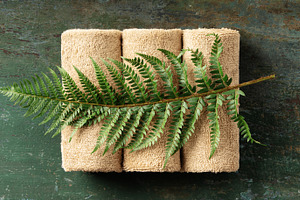 Natural Spa Towels with Green Fern Leaf on Rustic Wooden Backgro