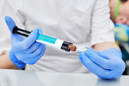 Dentist in Blue Gloves Preparing Cement for Tooth Crown. Detailed view highligh