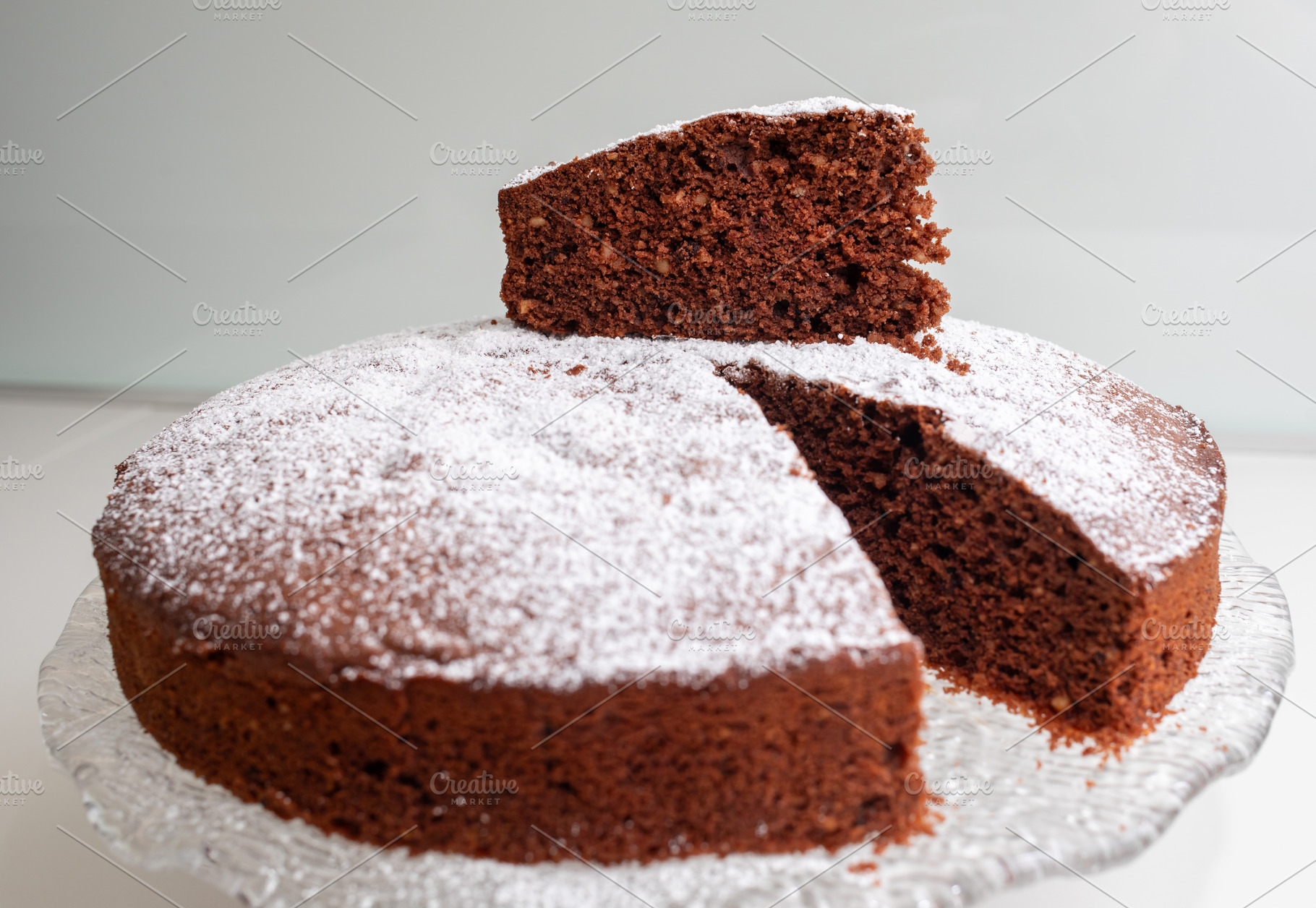 Delicious caprese cake with icing sugar and a cut slice showing its soft inside, a Food & Drink Photo by Antonio Gravante Market