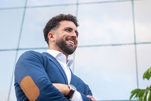 Confident businessman standing with crossed arms outside modern office, a Business Photo by etorres69