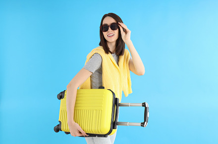 Attractive woman with travel bag on blue background, a Person Photo by AtlasStudio PRO
