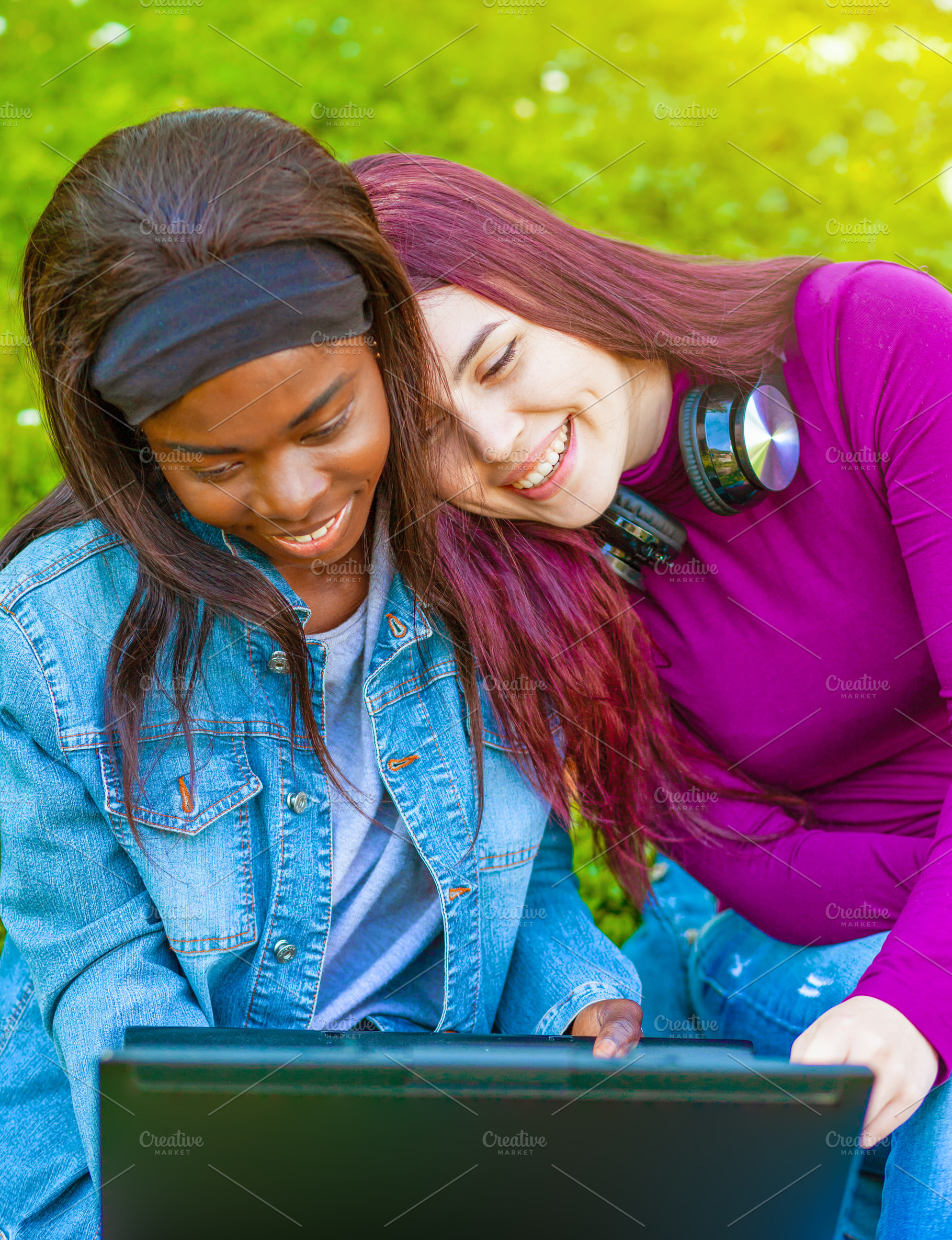 Two happy students using laptop and smiling in a park, a Person Photo by Antonio Gravante Market