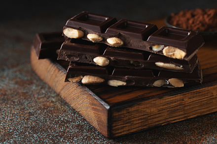 Dark and milk chocolate with nuts on a dark background sprinkled with cocoa pow, a Food & Drink Photo by Budarinphoto