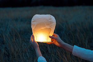 Female hands launching paper lantern into the sky, an Abstract Photo by AlyaAnd