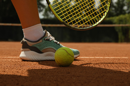 Woman leg, racket and tennis ball on clay court, a Sports & Recreation Photo by AtlasStudio PRO