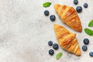 Delicious french croissants with fresh blueberries and mint on a, a Food & Drink Photo by Olena Rudo