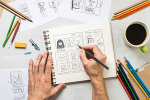 Persons hands drawing on a table a storyboard in a notebook, an Arts & Entertainment Photo by DanFLCreativo
