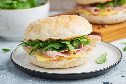 Two homemade sandwiches with ham, cheese and arugula on a concrete table., a Food & Drink Photo by Budarinphoto