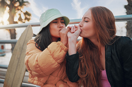 Playful, kiss and friends with a hand promise, support and secret in the city of California. Happy, together and women with affection, outdoor conversation and playing with happiness as besties, a Photo by Peopleimages.com