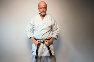 Martial artist gripping black belt while standing firmly., a Person Photo by karrastock