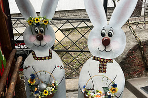 Decorative bunny figures holding festive baskets with flowers and eggs in sprin, a Photo by AS photostudio