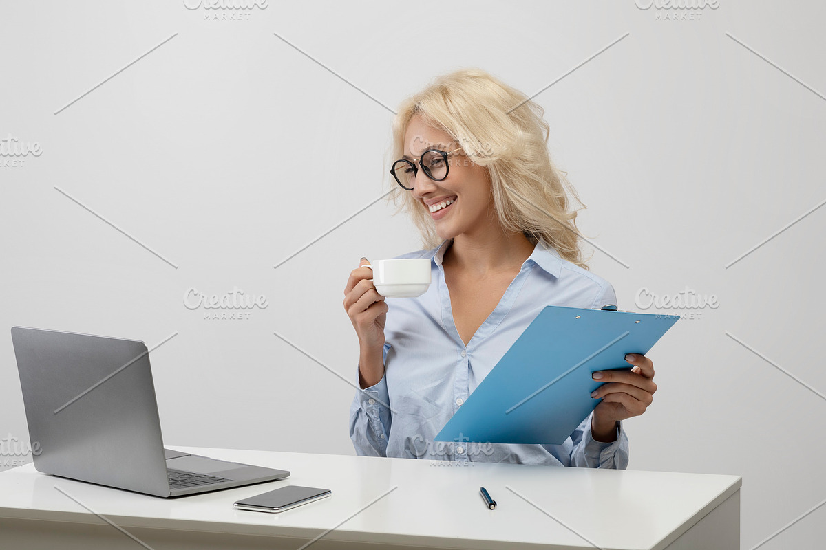 Business lifestyle. Happy office worker drinking coffee, working with documents, a Photo by Prostock-Studio (Photo 2 of 2)