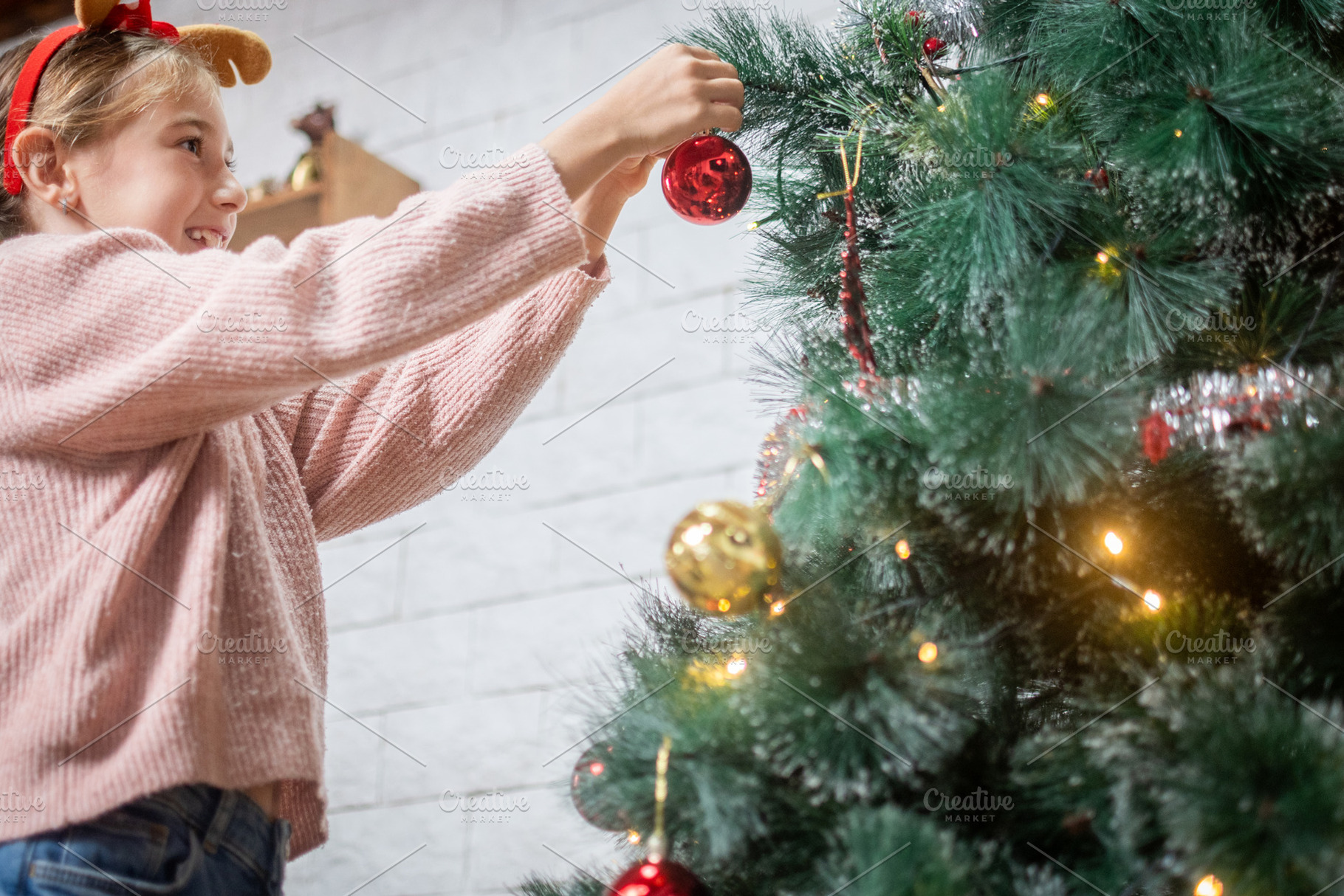 Smiling girl hanging red ornament on Christmas tree, a Holiday Photo by etorres69