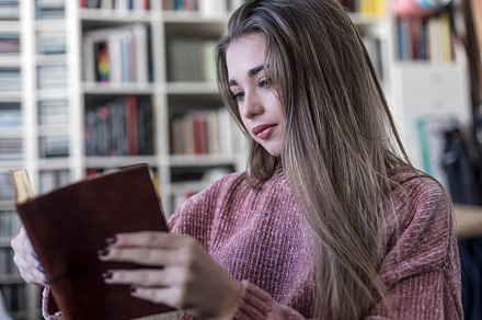 Relaxed woman reading a book on a sofa at home, a Person Photo by 2Design