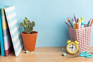 School desk with books, cactus, and stationery supplies